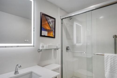 a white bathroom with a shower and a sink at Best Western Gregory Hotel in Brooklyn