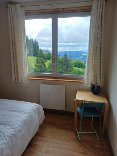 a bedroom with a bed and a desk and a window at Soleil Bleu in Saint-Racho