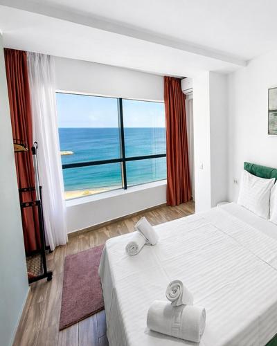 a bedroom with a large white bed and a large window at Olimp Sea View Apartments by Maritimo in Olimp