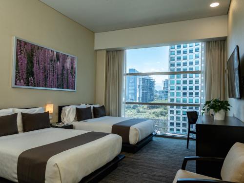 a hotel room with two beds and a large window at Stadia Suites Mexico City Santa Fe in Mexico City