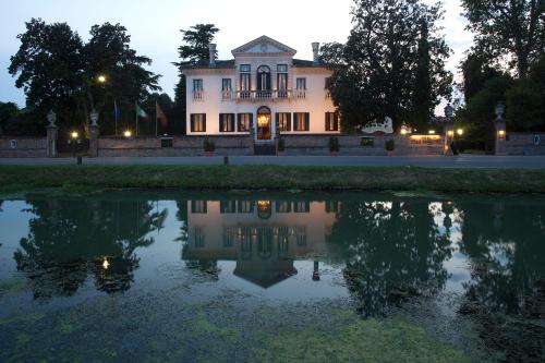 a building with a reflection in a pond at night at Villa Franceschi Hotel & Resort in Mira