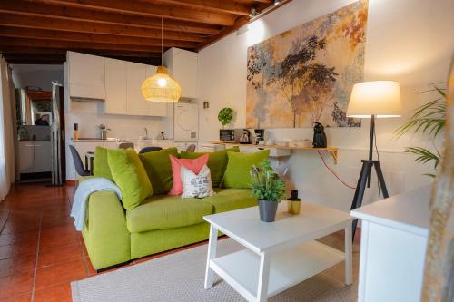 a living room with a green couch and a kitchen at El Rincón Del Huroncillo in Tejina