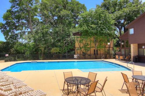 a swimming pool with tables and chairs next to a building at CW C107 Spritzen Haus in New Braunfels
