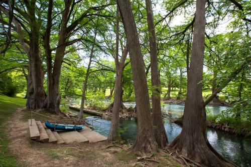 a blue canoe sitting on a dock next to a river at WW H303 Dreams and Streams in New Braunfels