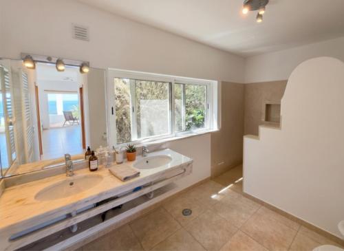 a bathroom with two sinks and a large window at Casa da Madrugada in Salema