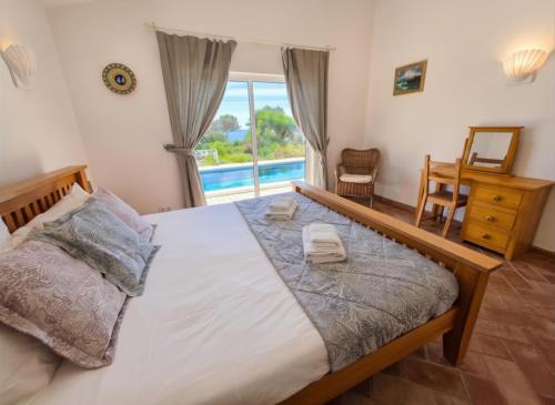 a bedroom with a bed and a desk and a window at Casa da Madrugada in Salema
