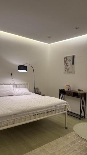 a white bedroom with a bed and a desk at وحده نجمة الفندقيه2 in Al Qurayyat