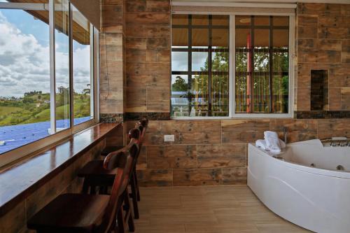 a bathroom with a tub and chairs and windows at Villa Jair Hotel in Filandia