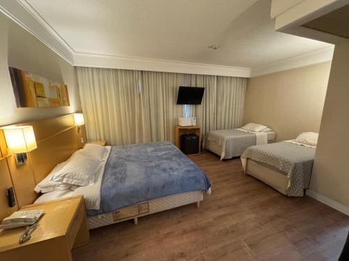 a hotel room with two beds and a television at Flat Guarulhos - 3 in Guarulhos