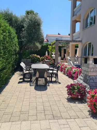 a patio with a table and chairs and flowers at Villa Rea in Malinska