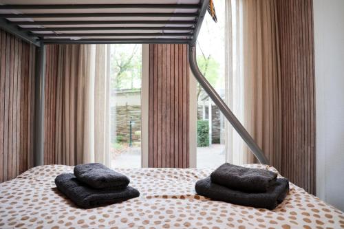 a bed with two pillows on it with a window at Sfeervol Boschalet 5 persoons met Sauna in Voorthuizen