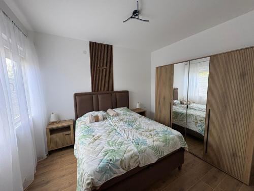 a bedroom with a large bed and a mirror at Divine Apartmani in Dobanovci