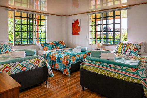 a room with three beds and a couch and windows at Villa Jair Hotel in Filandia