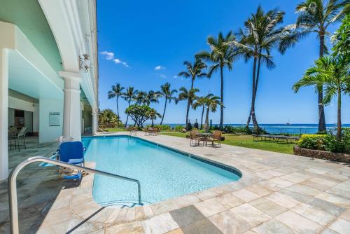 a swimming pool with palm trees and the ocean at Lahaina Shores 320 in Lahaina