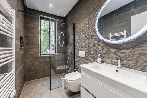 a bathroom with a toilet and a sink and a mirror at The Garden Jacuzzi Apartment By PS in Golem