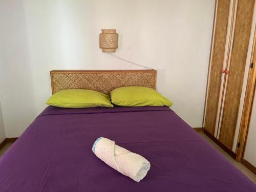 a pillow laying on a purple bed with yellow pillows at Pension Te Aroha - Te Haumaru in Maatea