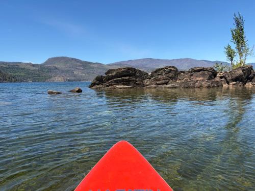 a red kayak in the water next to some rocks at Blind Bay Chalet 2 Bedroom Private Suite in Blind Bay
