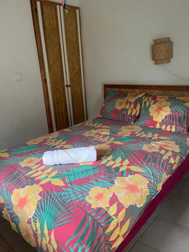 a bed with a colorful comforter on top of it at Pension Te Aroha - Te Rai in Maatea