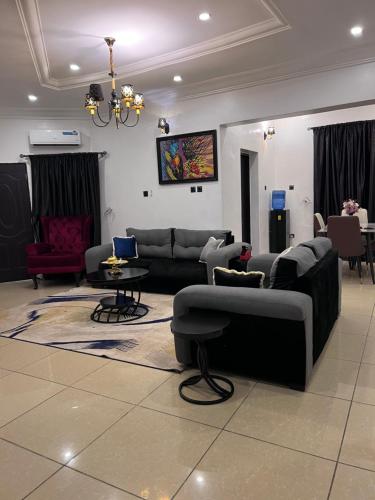 a living room with couches and tables and a tv at New Luxury in Gwarinpa
