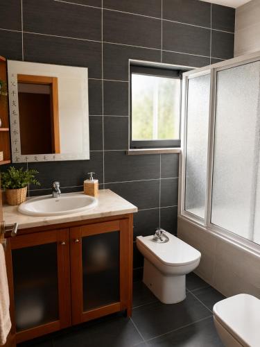 a bathroom with a sink and a toilet and a window at Entre Ilhas in Horta