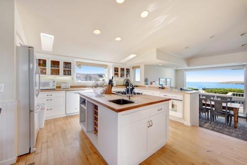 a large kitchen with white cabinets and a view of the ocean at Harbour House in Bodega Bay