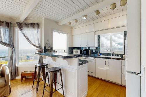 a kitchen with white cabinets and a large window at Sunset Escape in Bodega Bay