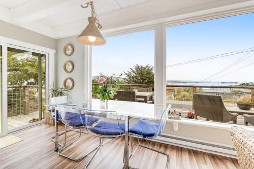 a dining room with a glass table and blue chairs at Whaleship Harbor View in Bodega Bay