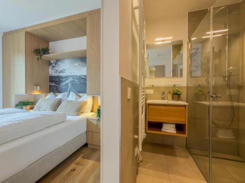 a bedroom with a bed and a shower and a sink at Birdie Lodge in Sankt Lambrecht