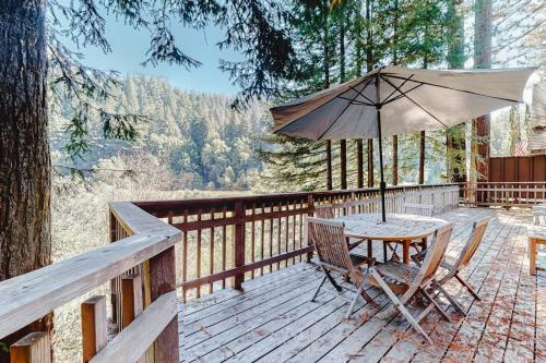 a table and chairs on a deck with an umbrella at Redwood Lodge in Monte Rio
