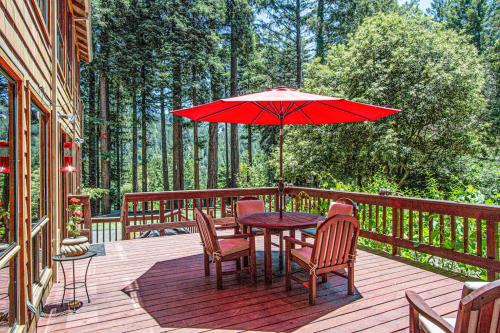 a wooden deck with a table and chairs and an umbrella at Sunrise Mountain Retreat in Cazadero