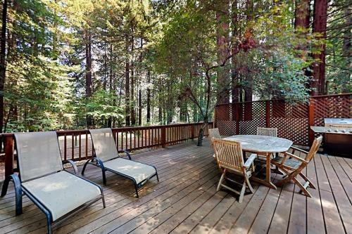 eine Holzterrasse mit Tisch und Stühlen in der Unterkunft Wagging Woods in Cazadero