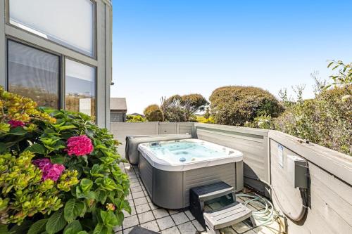a hot tub on the back of a house with flowers at Blue Horizon in Bodega Bay