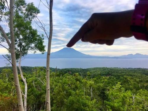 a hand pointing at a mountain in the distance at Rumah Pohon in Nusa Penida
