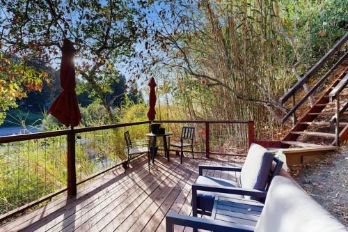 a wooden deck with chairs and a table and stairs at Rio Lindo River Retreat in Healdsburg