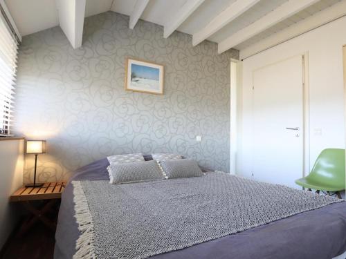 a bedroom with a bed and a green chair at Le Chemin des Framboises in Malmedy