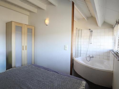 a bathroom with a tub and a bed and a bath tub at Le Chemin des Framboises in Malmedy