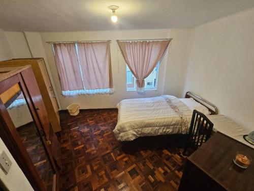 a bedroom with a bed and two windows and a wooden floor at Zona Sur, Bajo Seguencoma Flat in La Paz