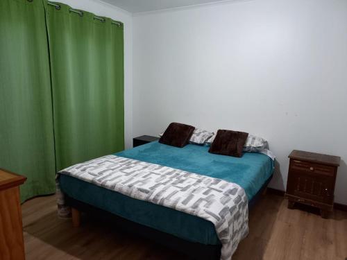 a bedroom with a bed and a green curtain at cabañas los treiles in Cumpeu