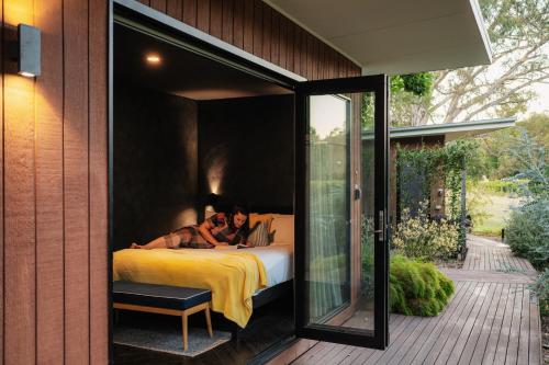 a woman laying on a bed in a glass house at Dal Zotto Homestead & Petite Retreats in Whitfield