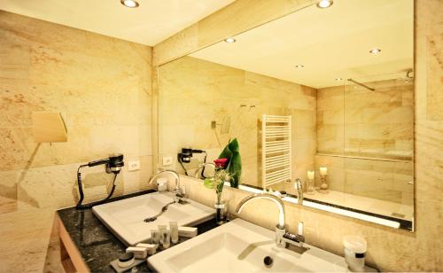baño con 2 lavabos y espejo grande en Salnerhof Superior Lifestyle Resort, en Ischgl
