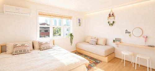 a bedroom with a bed and a couch and a window at All in one Guesthouse in Incheon