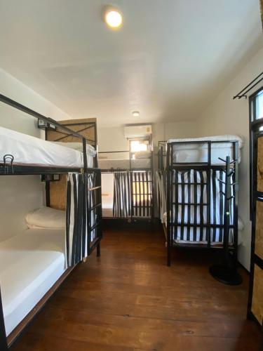 a room with three bunk beds and a wooden floor at Sherloft Home & Hostel in Chiang Mai