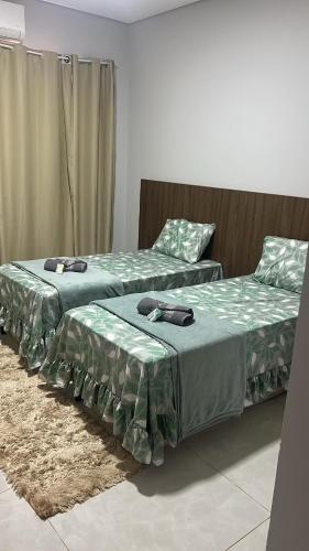 two beds sitting next to each other in a room at Casa de temporada Tarumã in Tangara da Serra