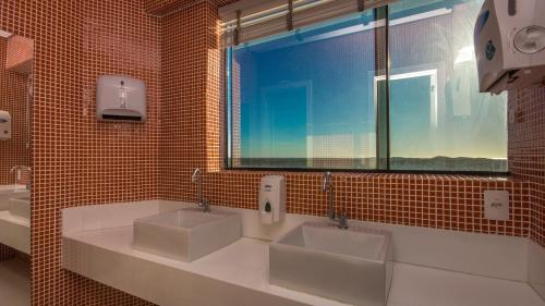 a bathroom with two sinks and a large window at Mais Hotel Aeroporto Salvador in Lauro de Freitas