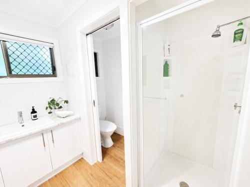 a white bathroom with a shower and a toilet at Hidden Gem at The Bay - Resort Pool - 300m to Beach in Urangan