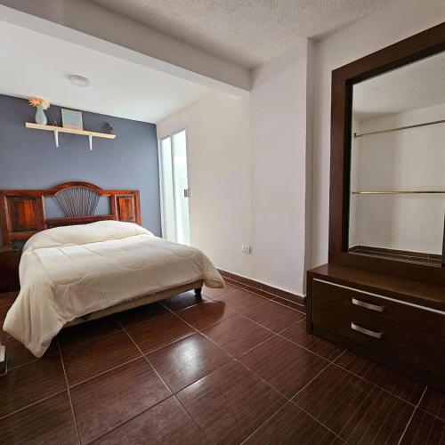 a bedroom with a bed and a dresser and a mirror at Isabella's Cottage in Cholula