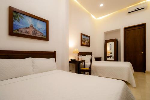 a bedroom with two beds and a tv on the wall at El Navegante in Campeche