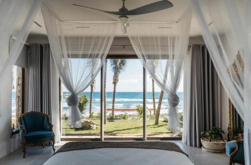 a bedroom with a bed and a view of the ocean at 5BR Exclusive Beachfront Villa with Pool in Tulum in Balcheil