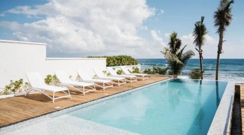 a pool with chairs and the ocean in the background at 5BR Exclusive Beachfront Villa with Pool in Tulum in Balcheil