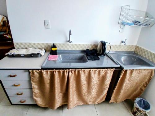 a kitchen counter with a sink with a copper curtain over it at Conforto e Praticidade, Studio para 2 pessoas in Ponta Grossa